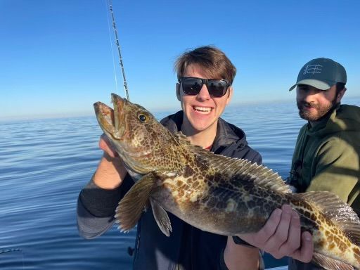 A man is holding a large fish in his hands on a boat.