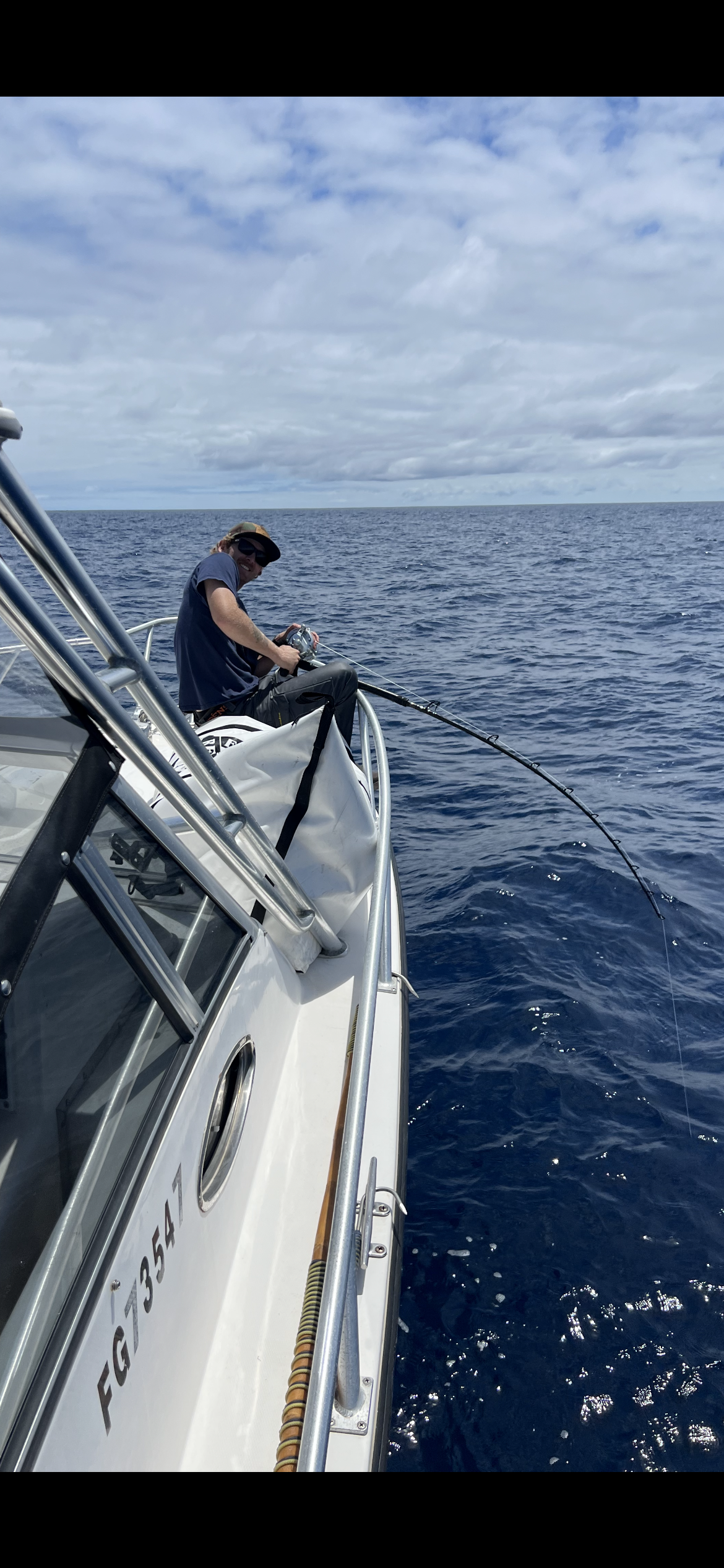 A man is fishing on a boat in the ocean.