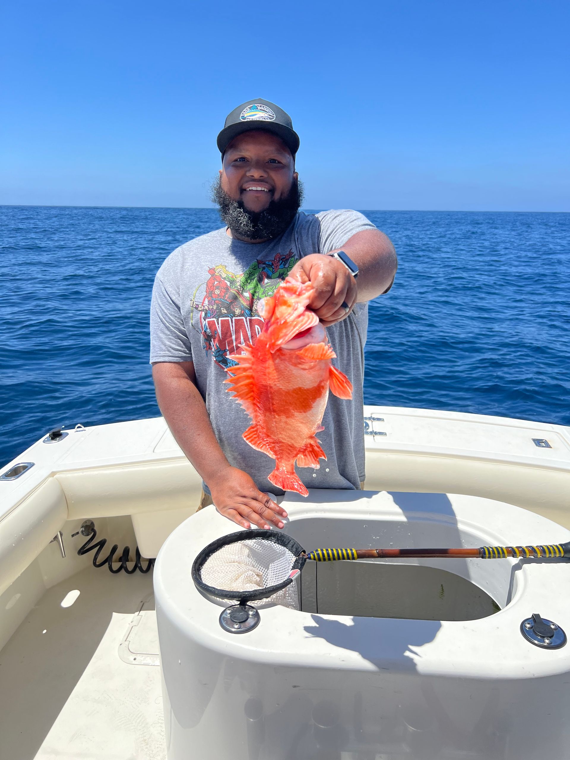 A man is holding a fish on a boat in the ocean.