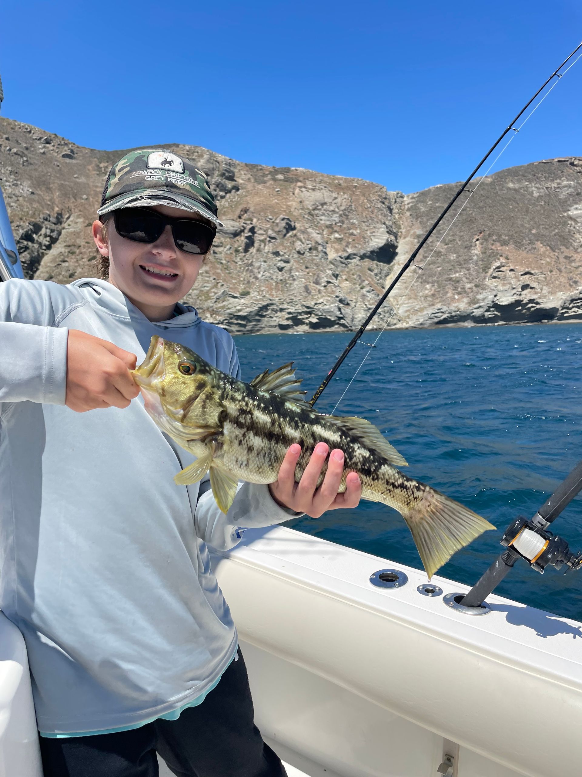 A young boy is holding a fish on a boat.