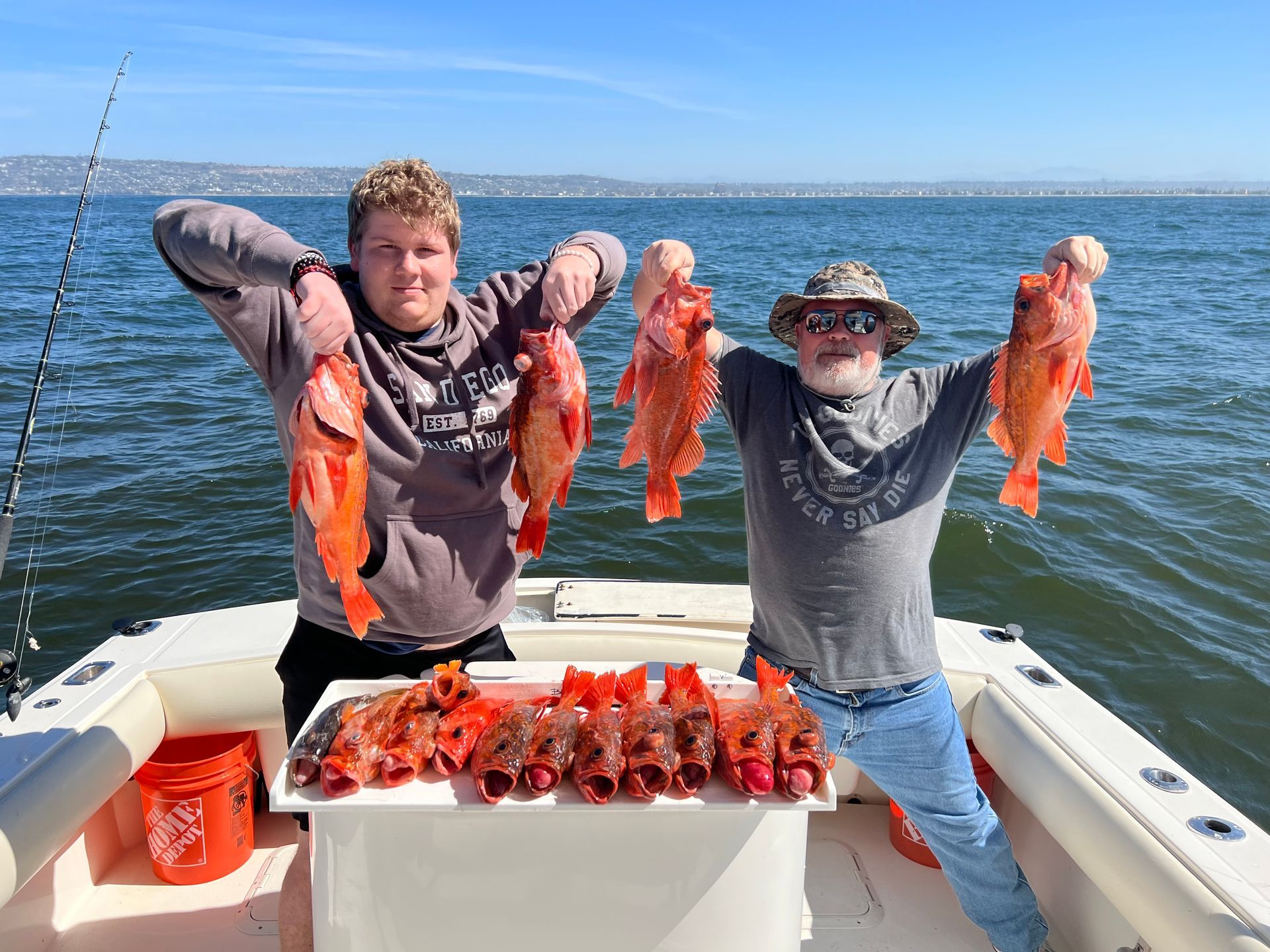 Two men are standing on a boat holding fish in their hands.