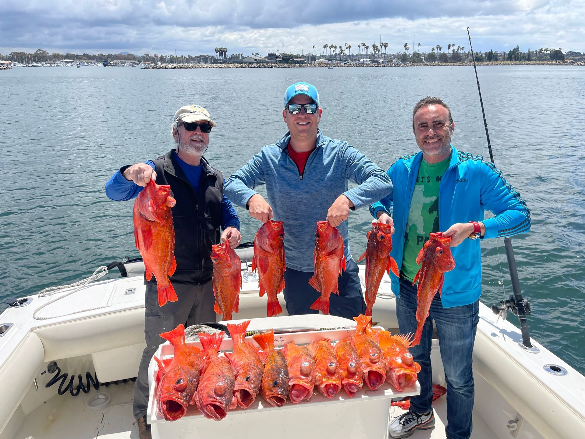 Three men are standing on a boat holding fish.