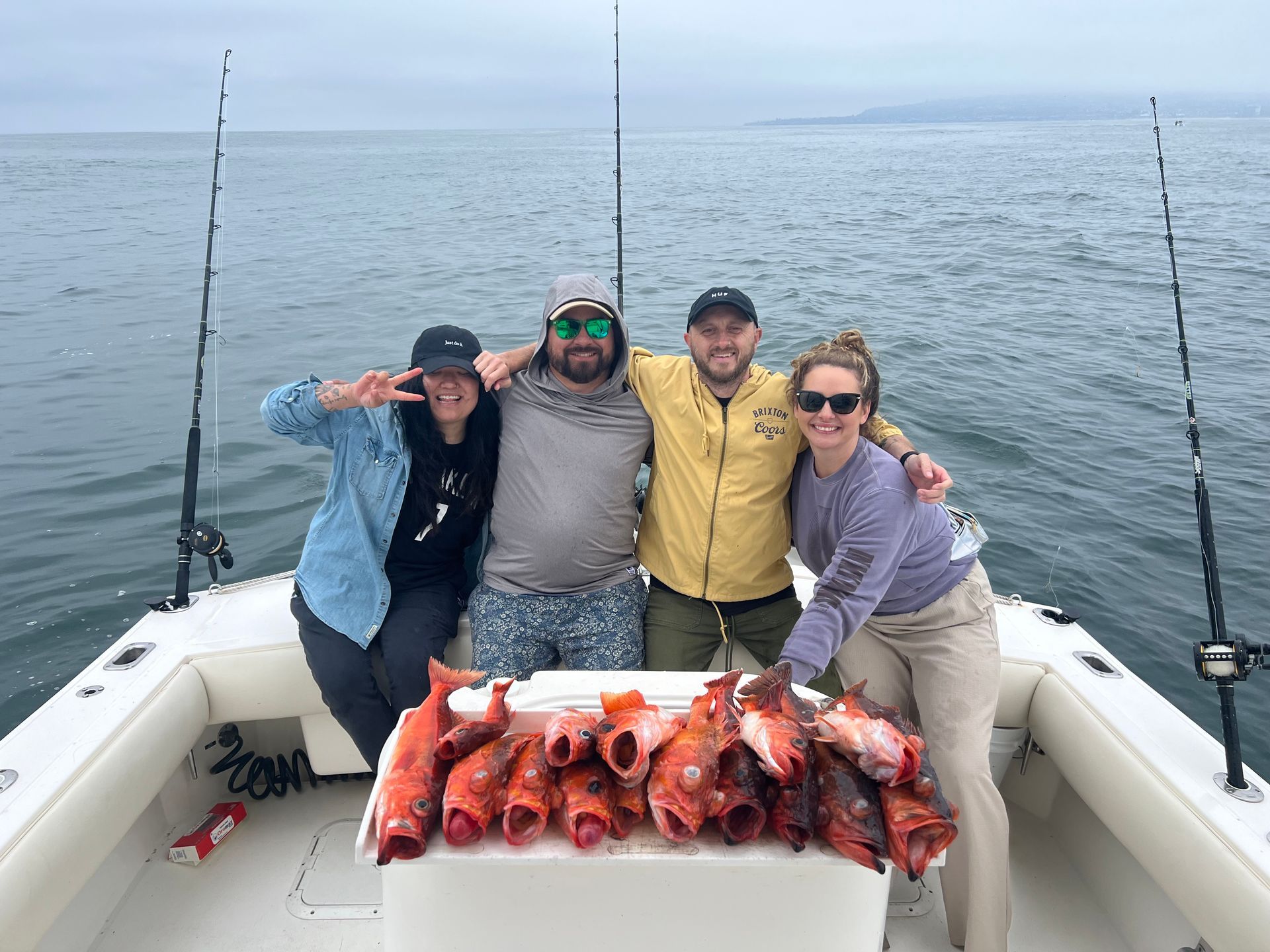 A group of people are standing on a boat holding fish.