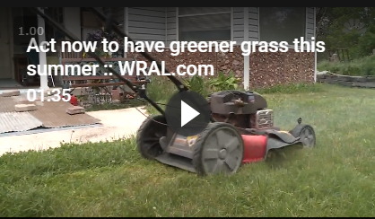 A lawn mower is cutting grass in front of a house.