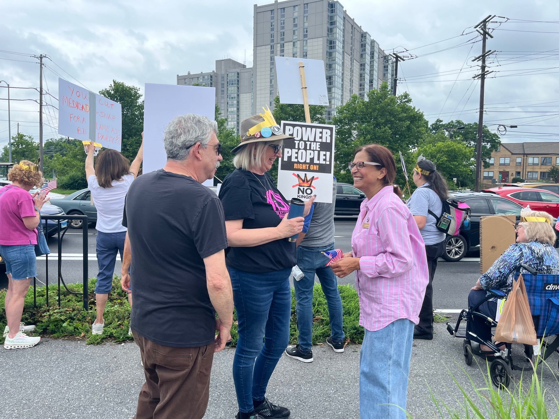 A group of people are standing in a parking lot holding signs that say power to the people.
