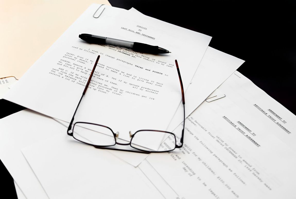 Glasses and pen resting on a pile of documents