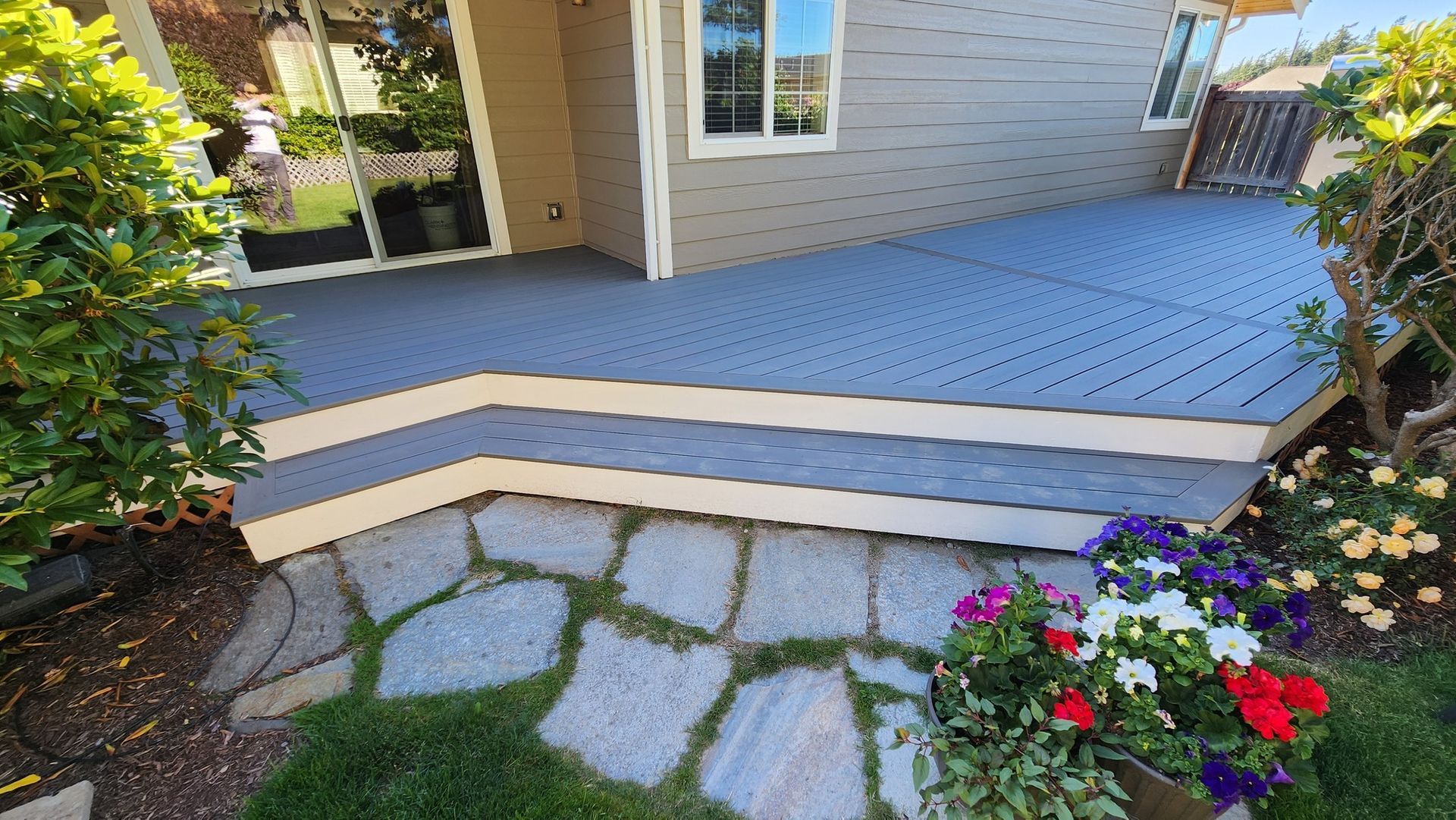 A blue deck with stairs and flowers in front of a house.