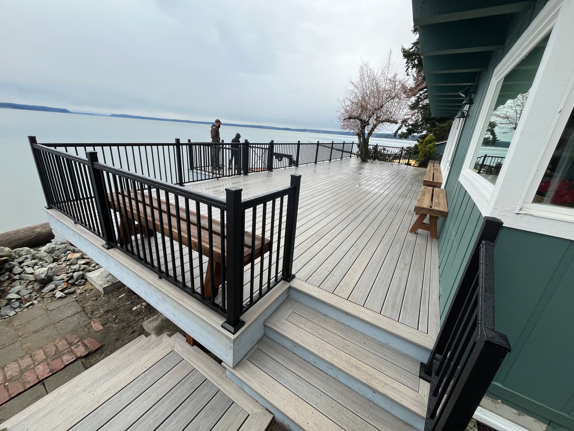 A large wooden deck with stairs leading up to it overlooking the water.