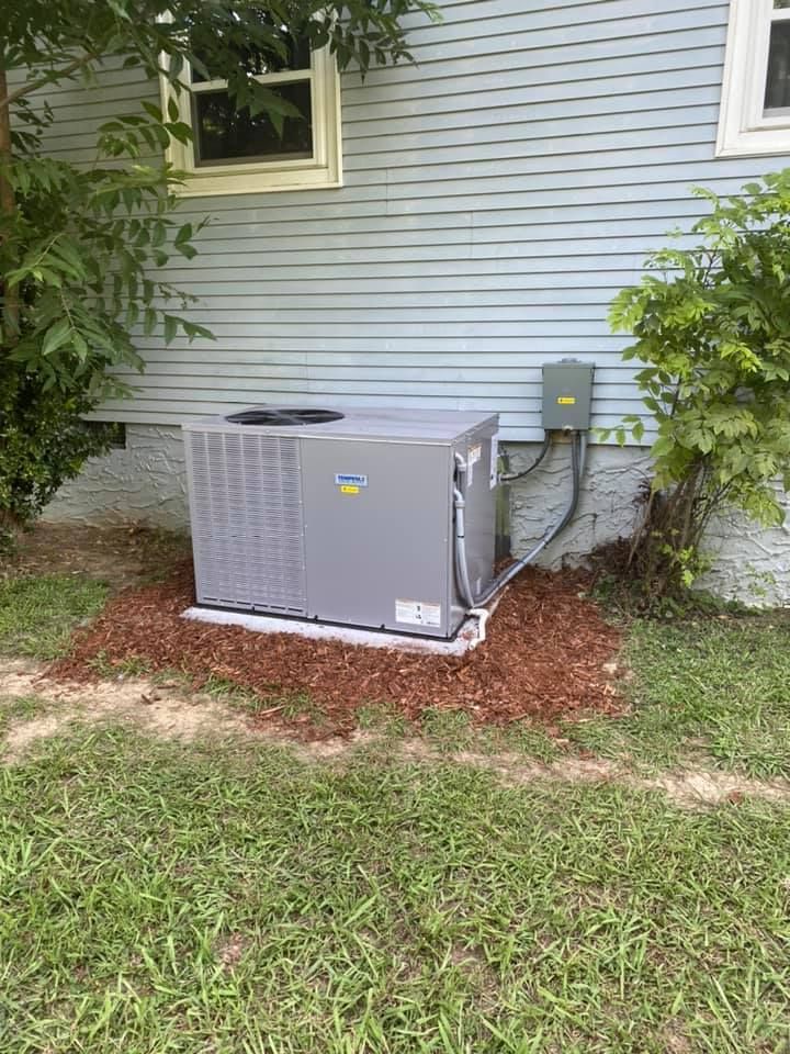 An air conditioner is sitting on the side of a house.