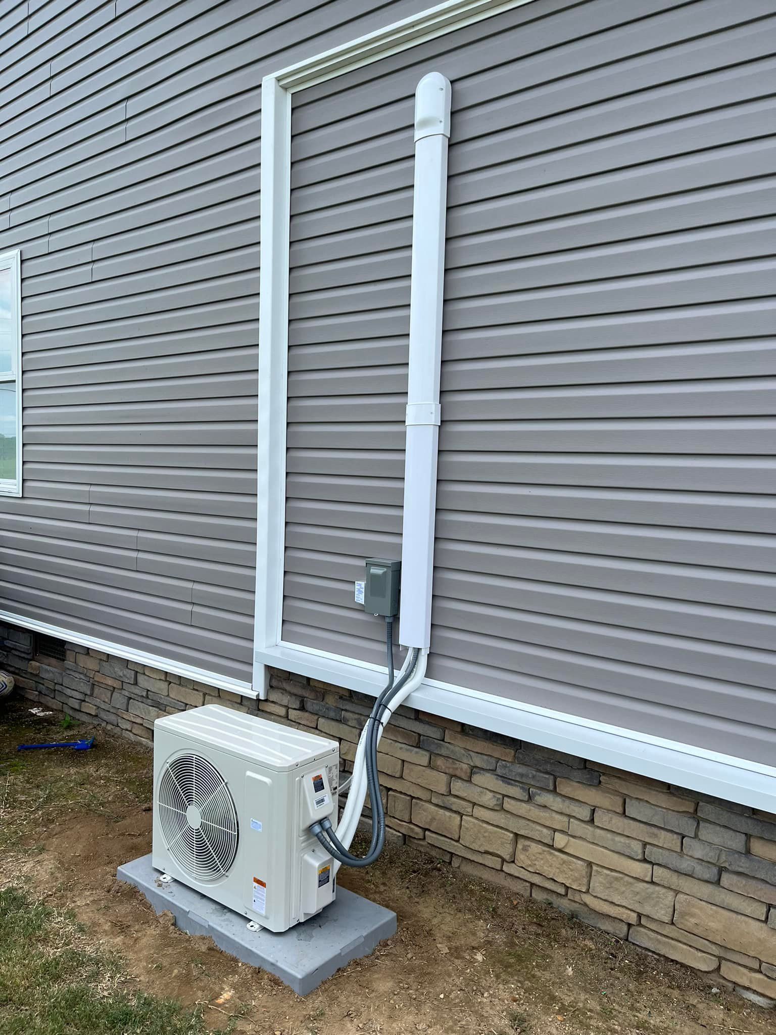 A white air conditioner is sitting on the side of a house.