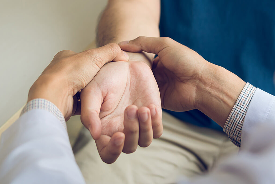 Doctor examining a patient's wrist, palpating the area with both hands.W