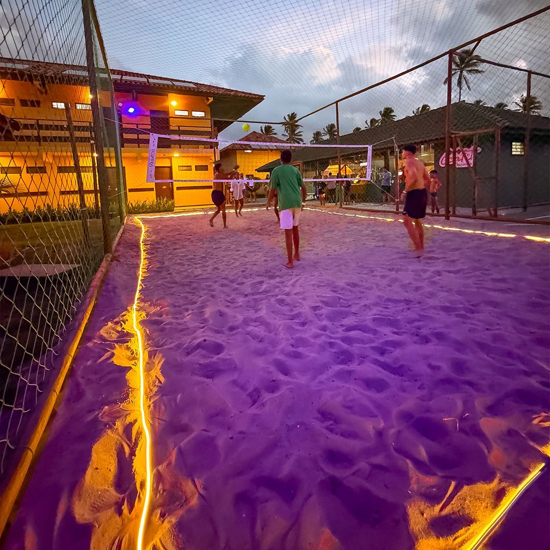 Um homem de camisa azul e chapéu branco está parado em frente a uma parede colorida.