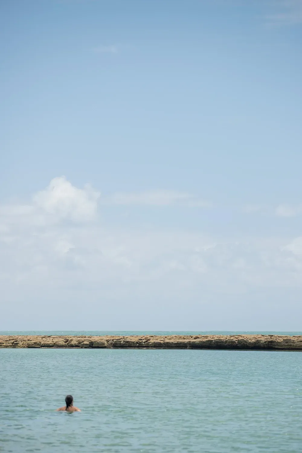 Um homem está nadando no oceano em um dia ensolarado.