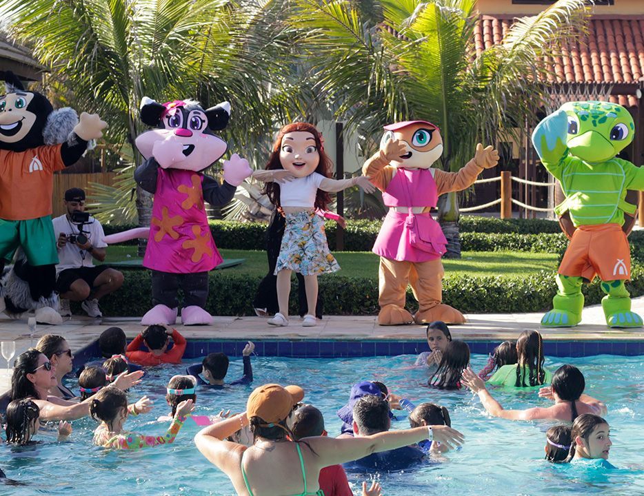 Um grupo de pessoas usando chapéus de Papai Noel estão posando para uma foto em frente a uma piscina.