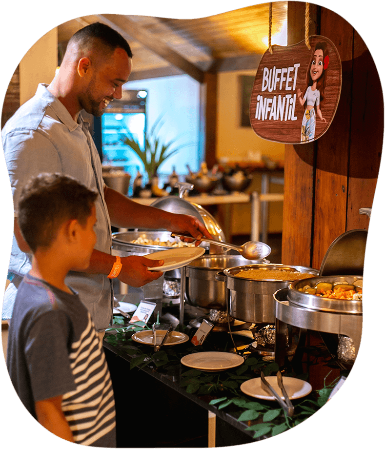 Um homem e um menino estão de pé em uma mesa de bufê.