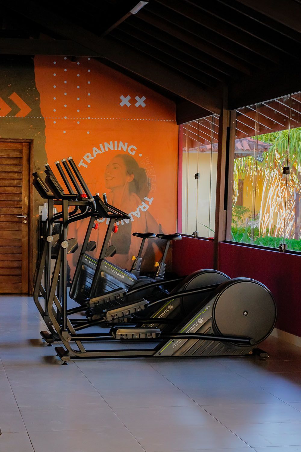 Uma academia com muitos equipamentos de exercícios e uma grande janela.