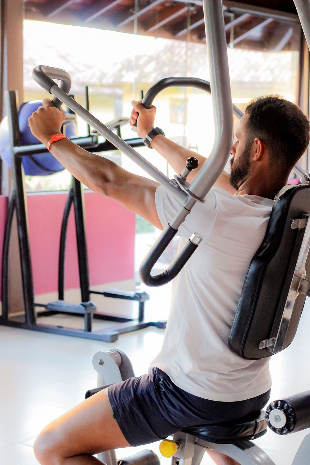 Um homem está sentado em uma máquina em uma academia.