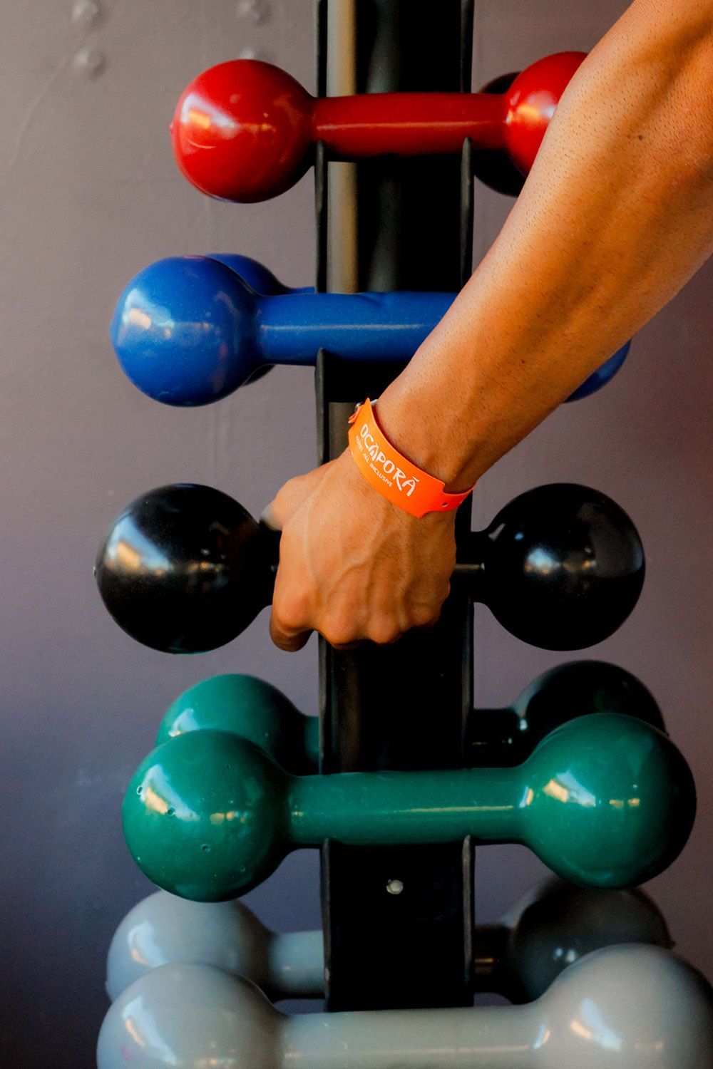 Uma pessoa segurando um haltere com uma pulseira laranja que diz apoio
