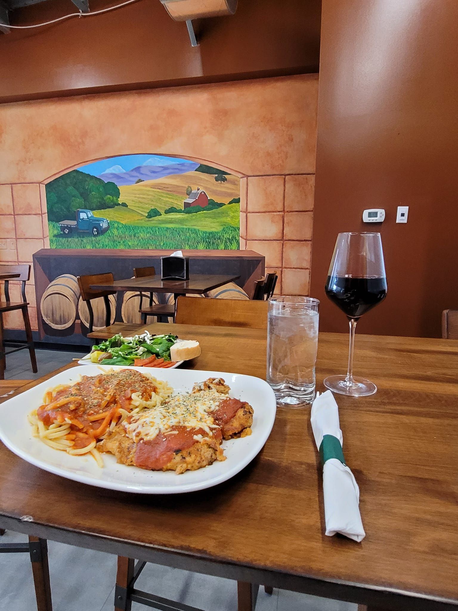 A plate of food is sitting on a wooden table next to a glass of wine.