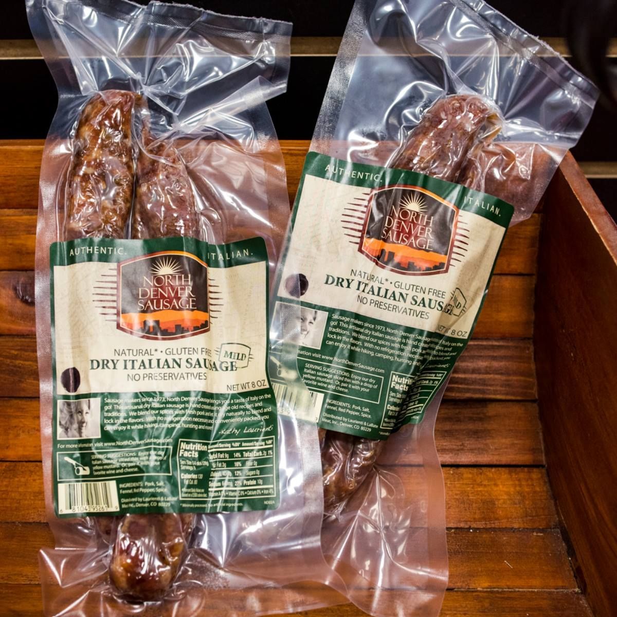 Two bags of dry italian sausage are sitting on a wooden table.