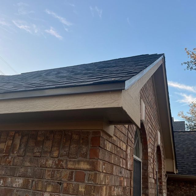 A brick house with a black roof and a window