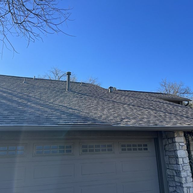 The roof of a house with a garage door and a blue sky in the background.