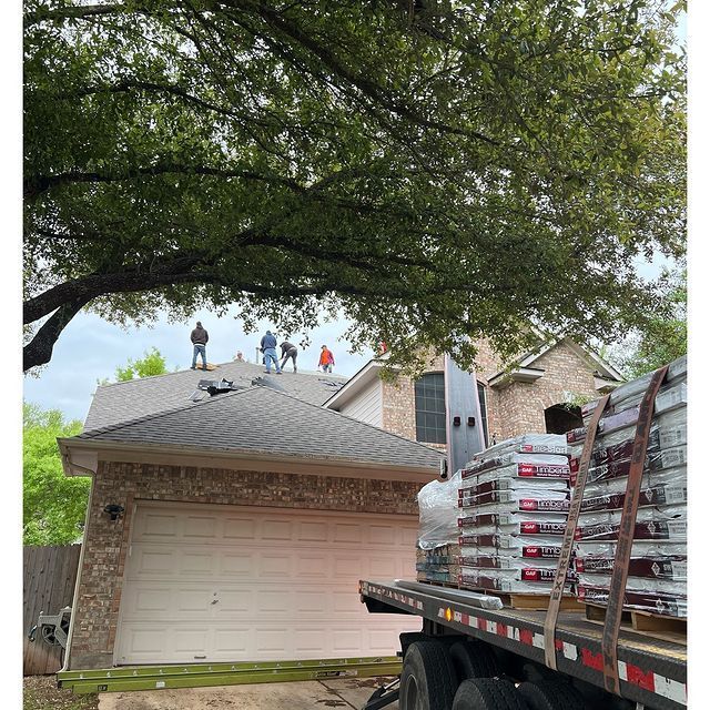A truck is carrying a stack of shingles on the back of it.