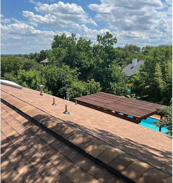 The roof of a house with a pool and trees in the background
