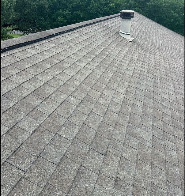 A close up of a roof with shingles and a chimney.