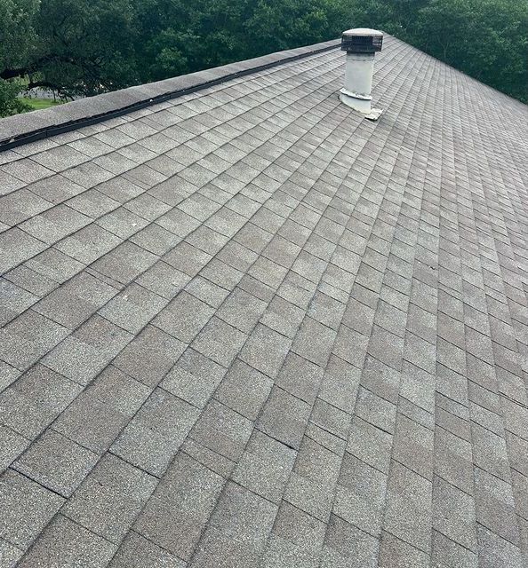 A close up of a roof with shingles and a chimney.