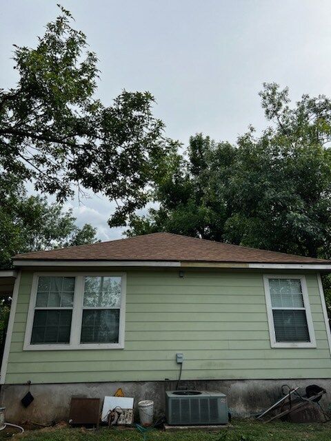 A green house with a brown roof and white windows