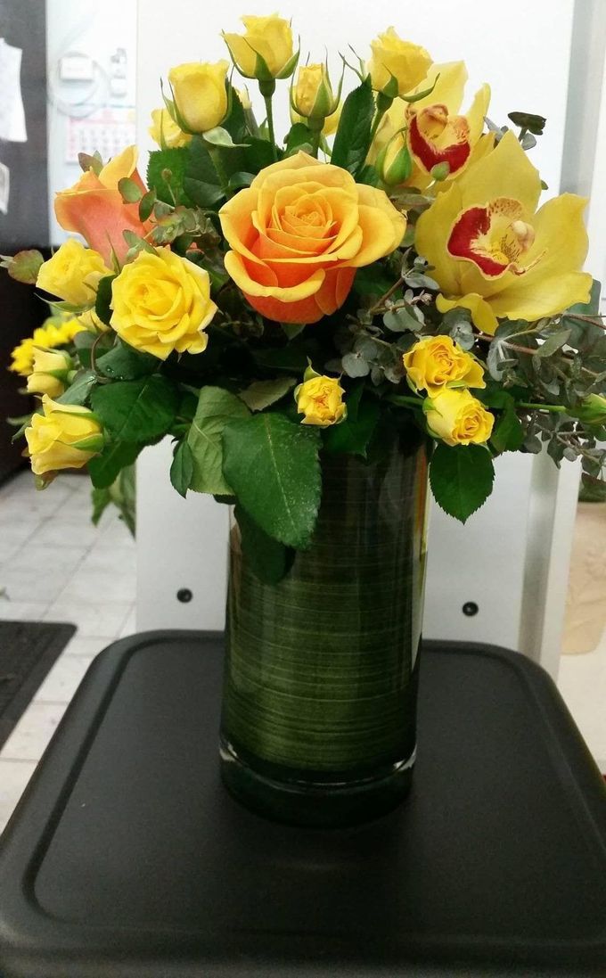 A Vase Filled With Yellow Roses and Orchids is Sitting on a Table — The Flower Station Townsville In Kirwan, QLD A Vase Filled With Yellow Roses and Orchids is Sitting on a Table — The Flower Station Townsville In Kirwan, QLD