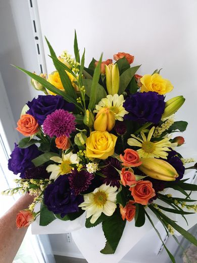 A Woman is Making a Bouquet of Flowers on a Wooden Table — The Flower Station Townsville In Kirwan, QLD