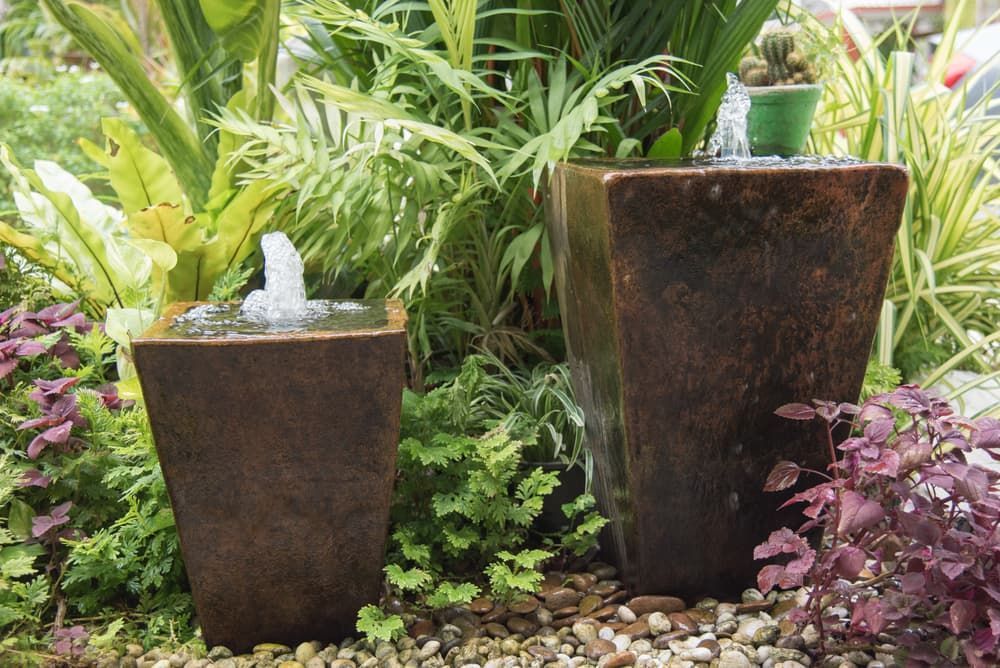 Two Potted Plants Are Sitting Next to a Fountain in a Garden — The Flower Station Townsville In Kirwan, QLD