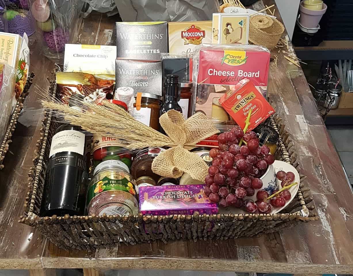 A Wicker Basket Filled With Food and Wine on a Wooden Table — The Flower Station Townsville In Kirwan, QLD A Wicker Basket Filled With Food and Wine on a Wooden Table — The Flower Station Townsville In Kirwan, QLD