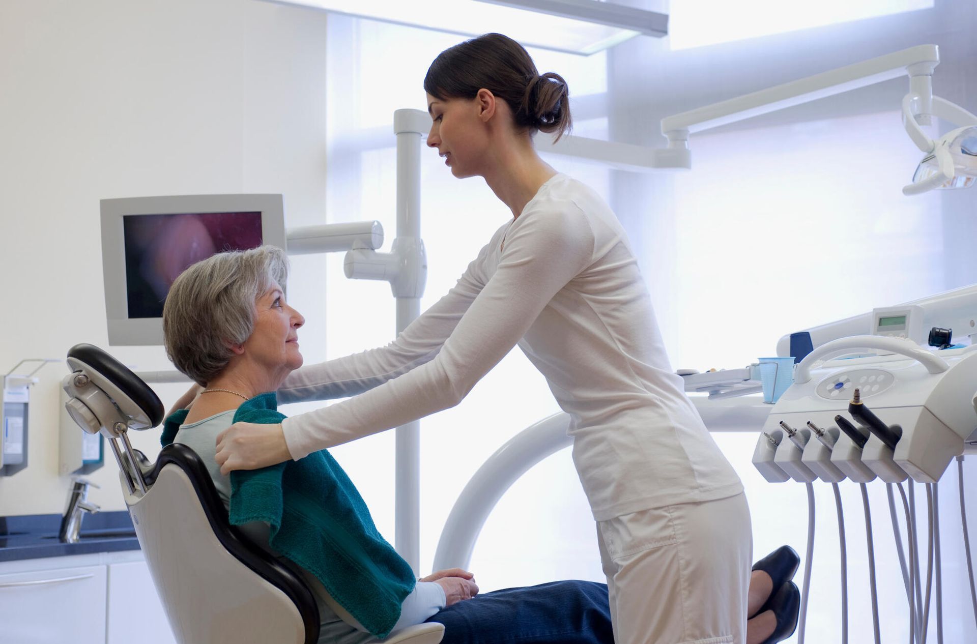 A dentist is talking to a patient in a dental chair.