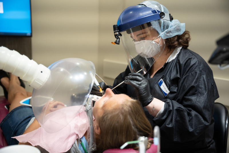 A dentist is examining a patient 's teeth in a dental office.