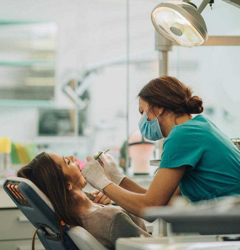 A woman is getting her teeth examined by a dentist