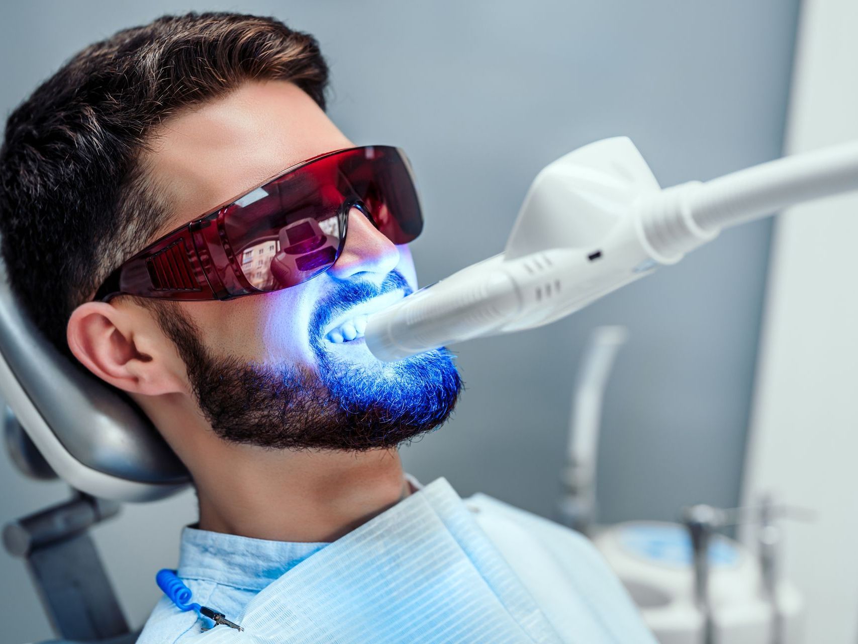 A man is getting his teeth whitened at the dentist.