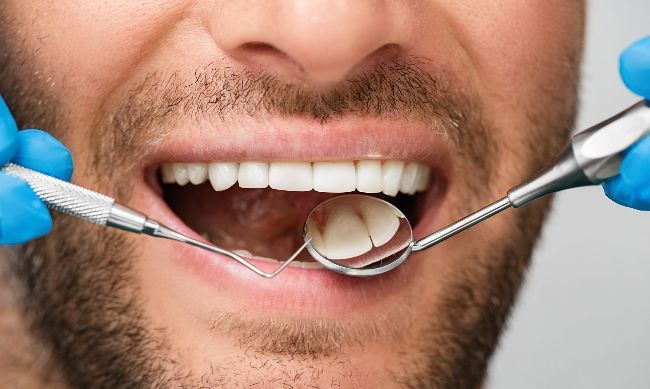 A man is getting his teeth examined by a dentist.