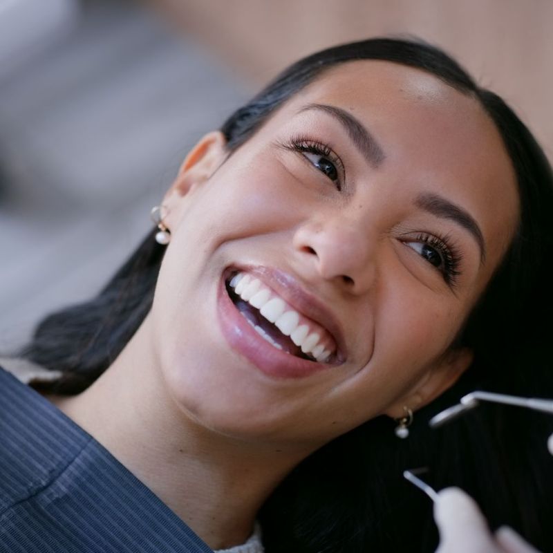 A woman is smiling while having her teeth examined by a dentist