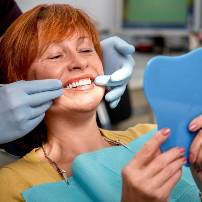 A woman is looking at her teeth in a mirror