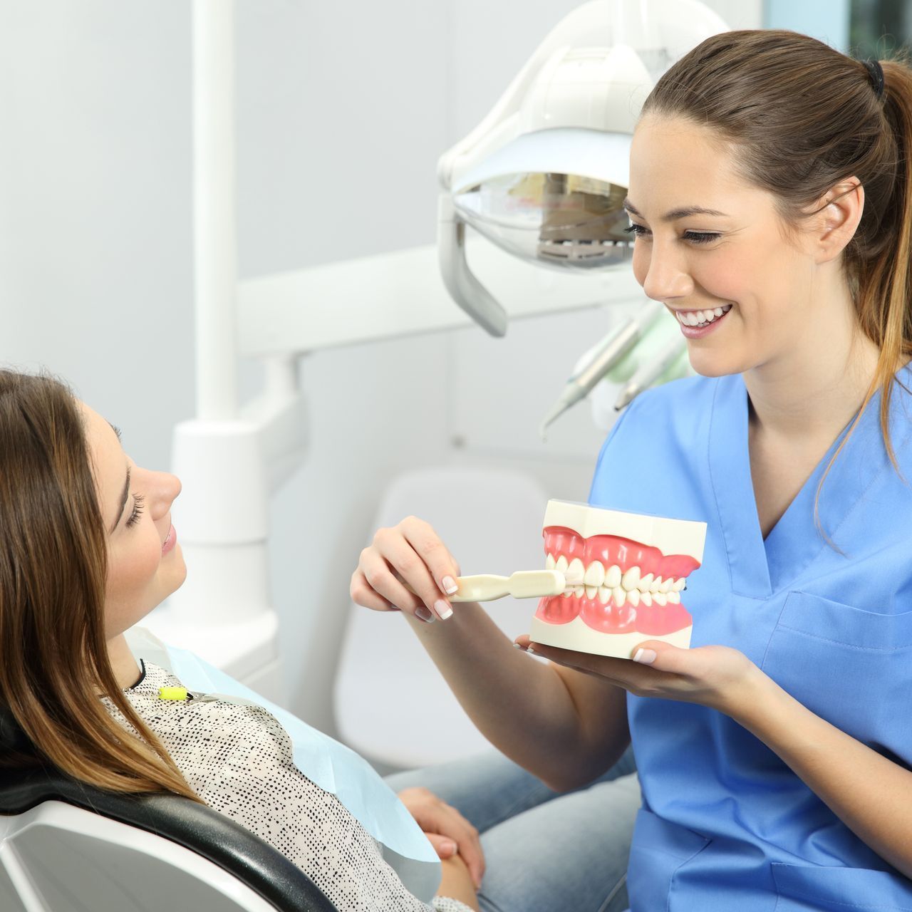 A female dentist is showing a model of teeth to a patient