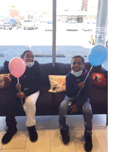 2 african american kids smiling holding balloons