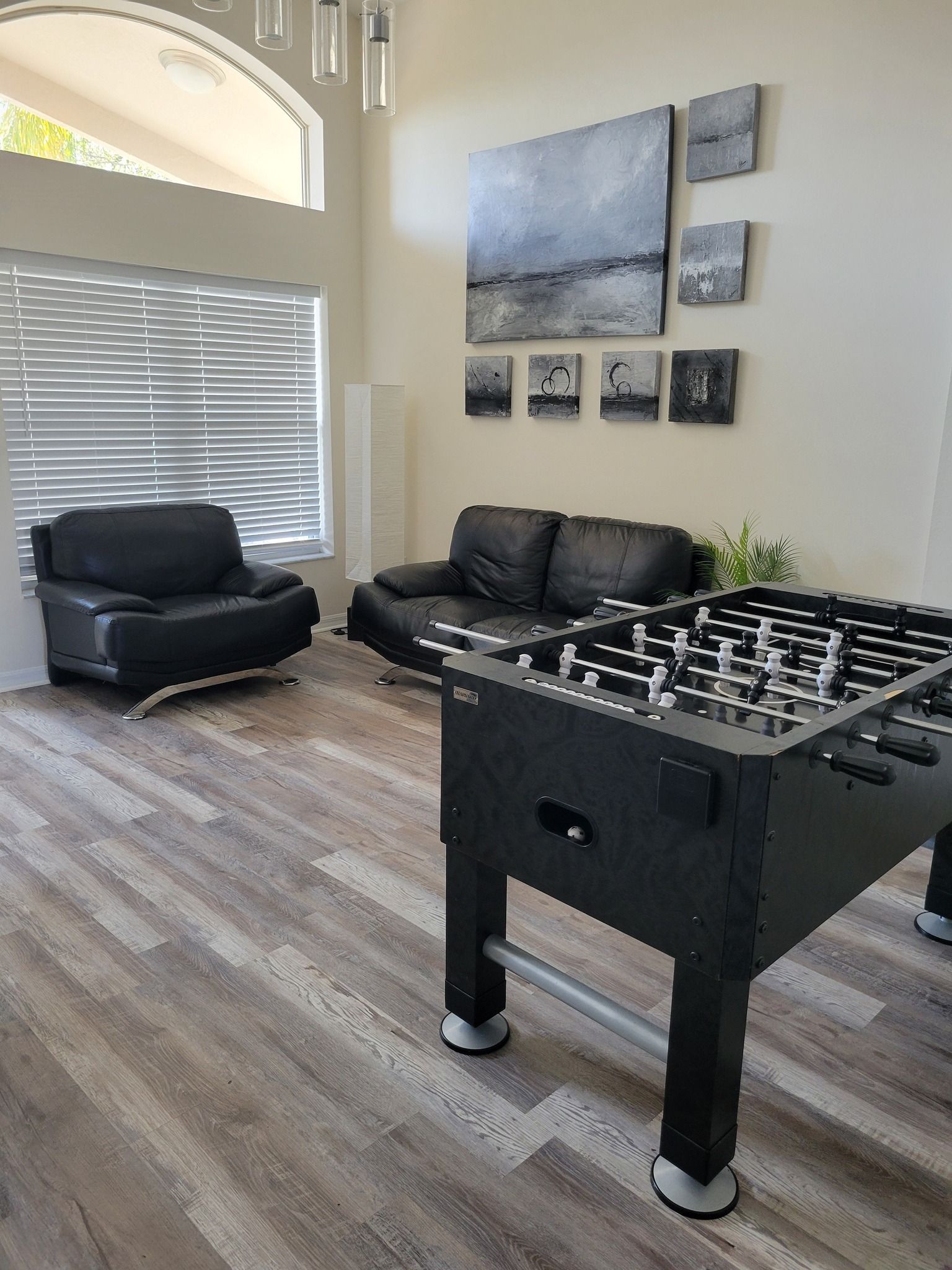 A living room with a foosball table and a couch.