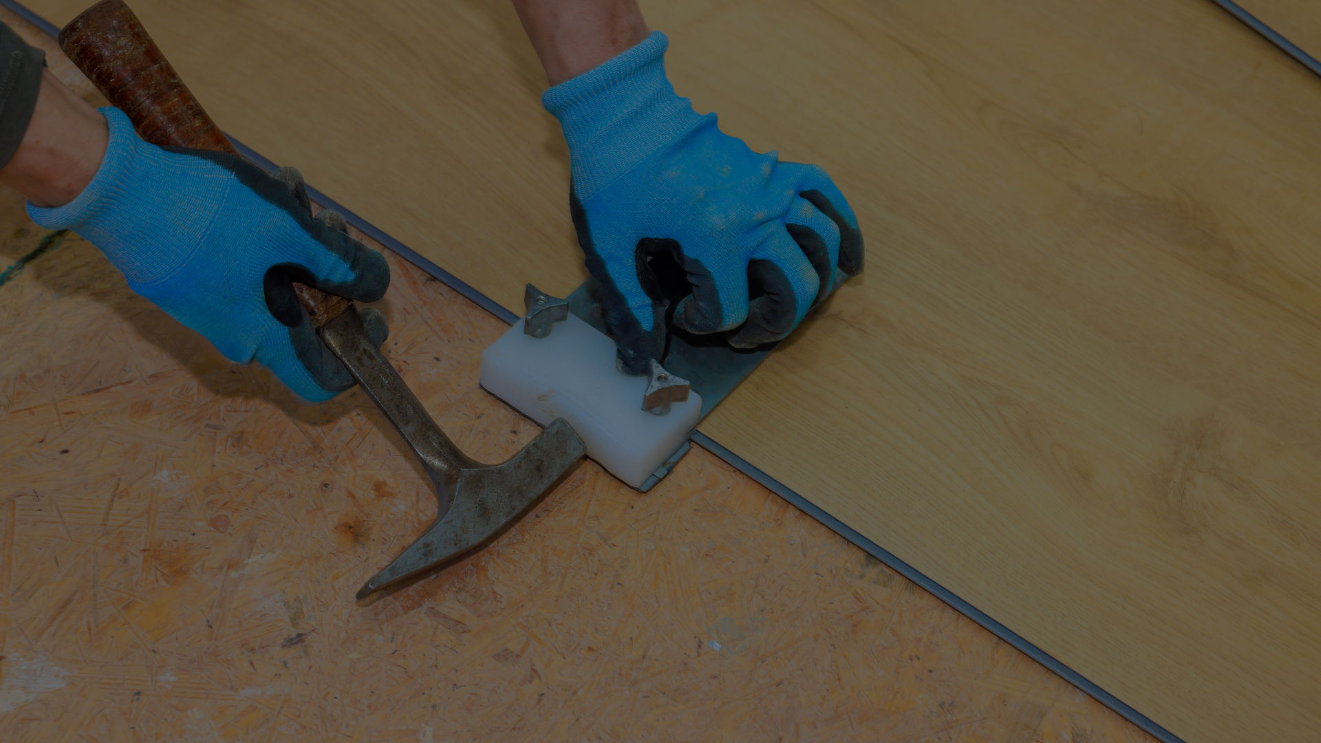A person is holding a hammer and a sponge on a wooden floor.