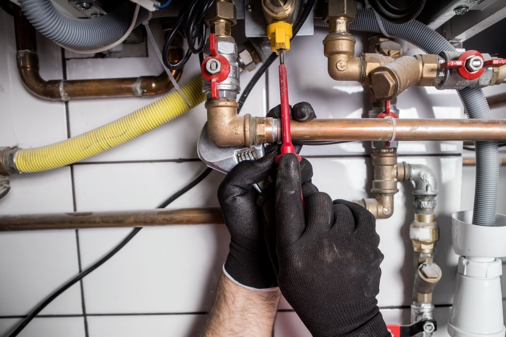 Hands Tightening a Valve on Exposed Plumbing With a Red Wrench — New Gen Plumbing and Gas in Banora Point, NSW