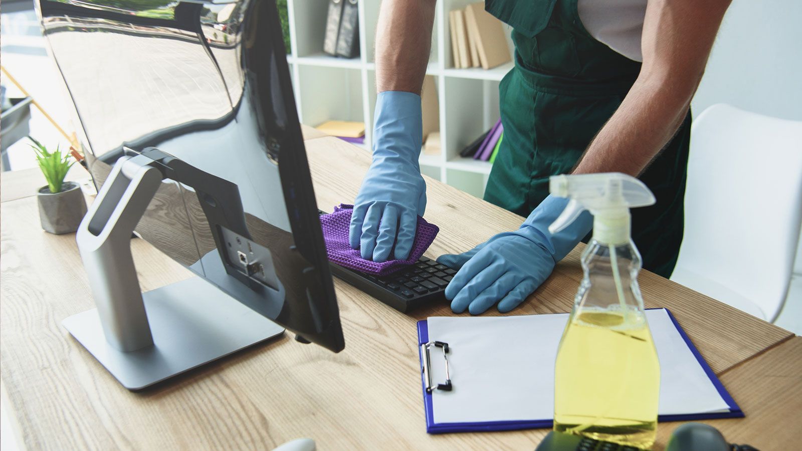 A person is cleaning a computer keyboard with a cloth.