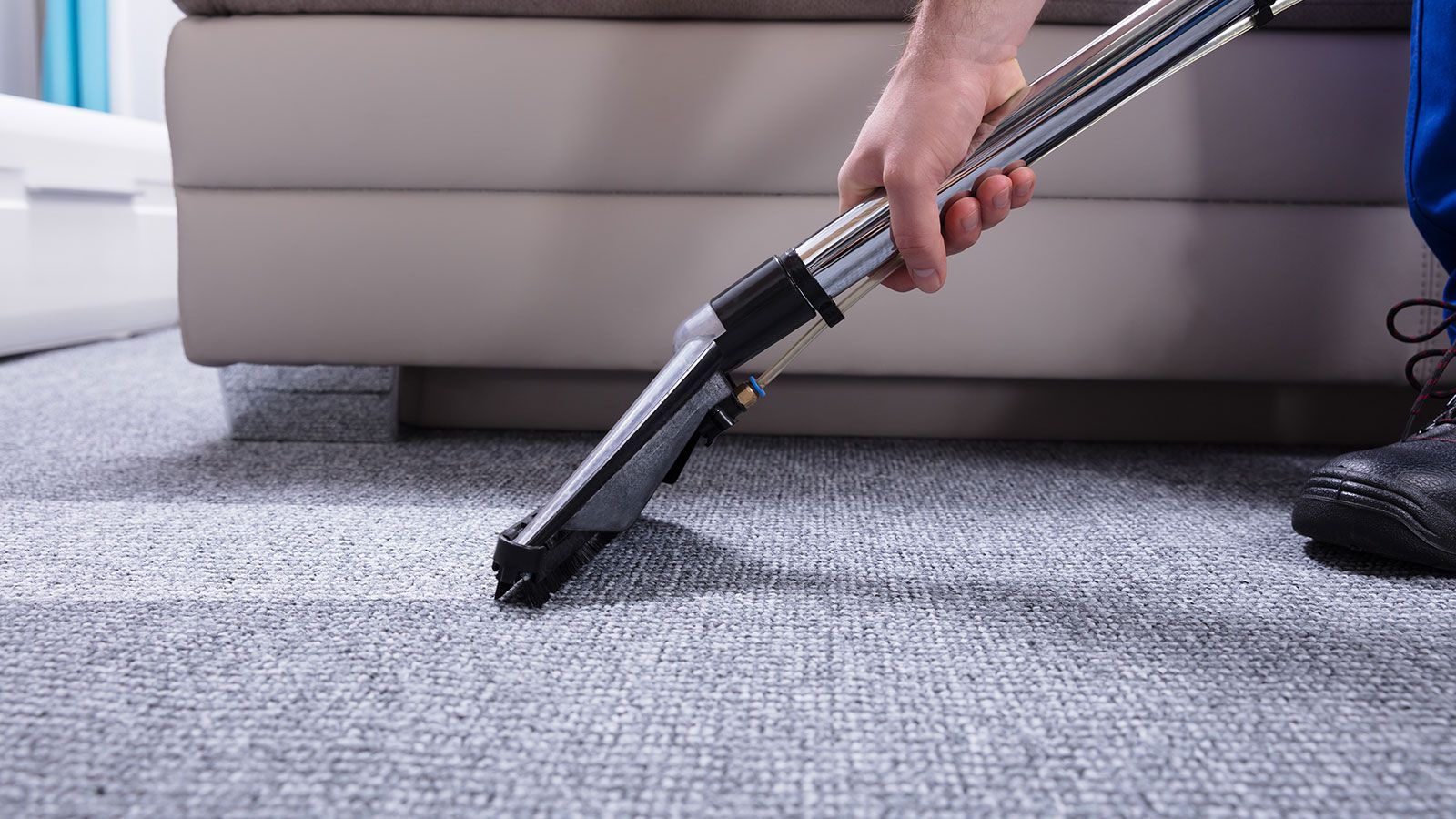 A person is cleaning a carpet with a vacuum cleaner.