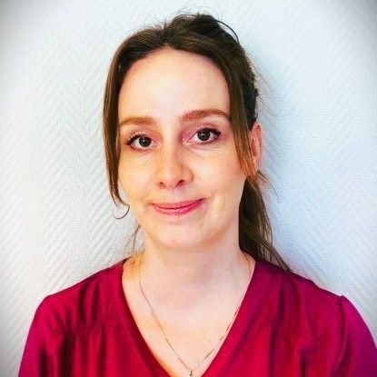 Tannlege Christian med briller og skjegg, iført blå skjorte og medisinsk maske, smiler til kameraet.